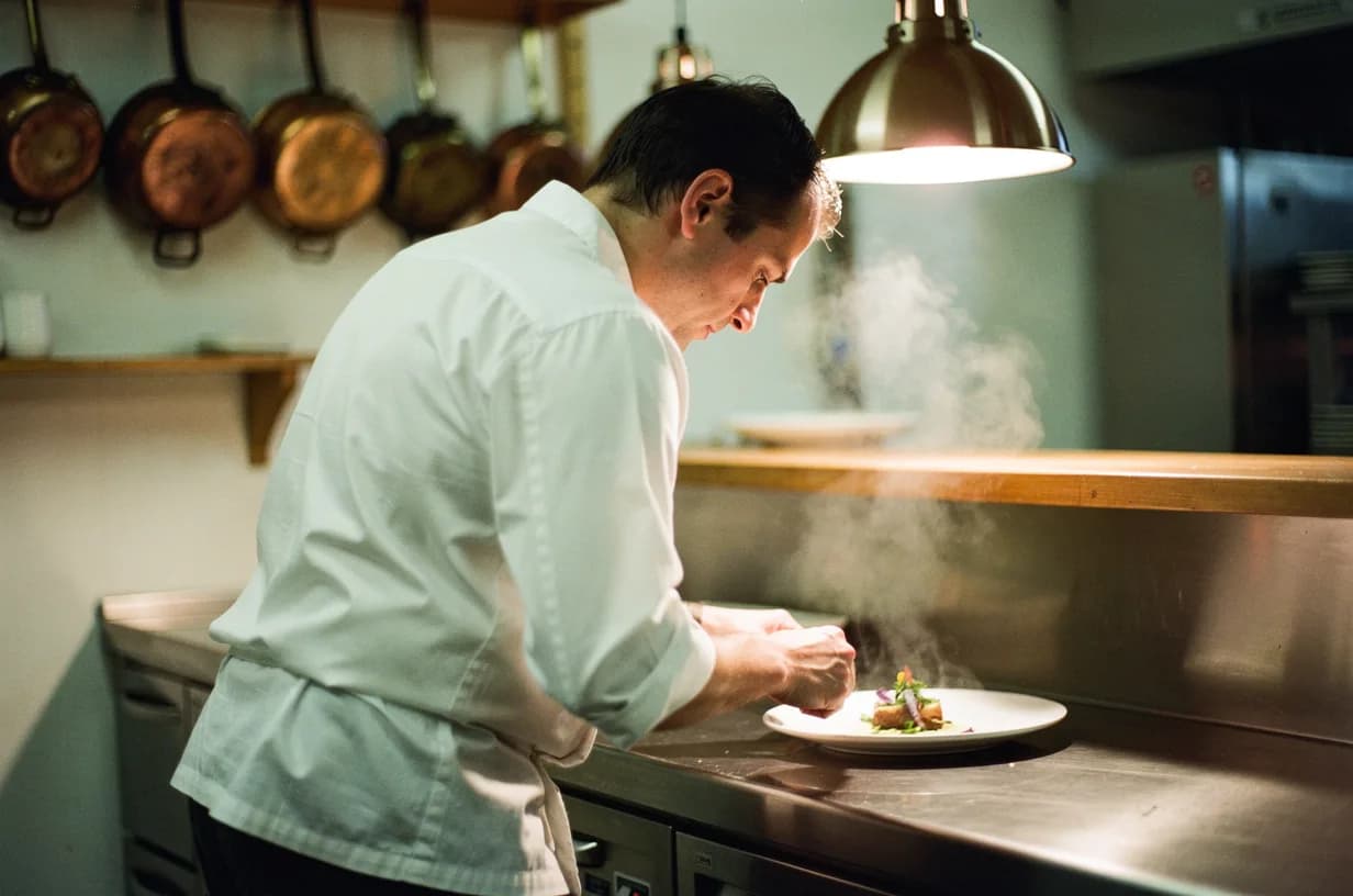 Cuisinier dressant une assiette au passe d'une cuisine de restaurant
